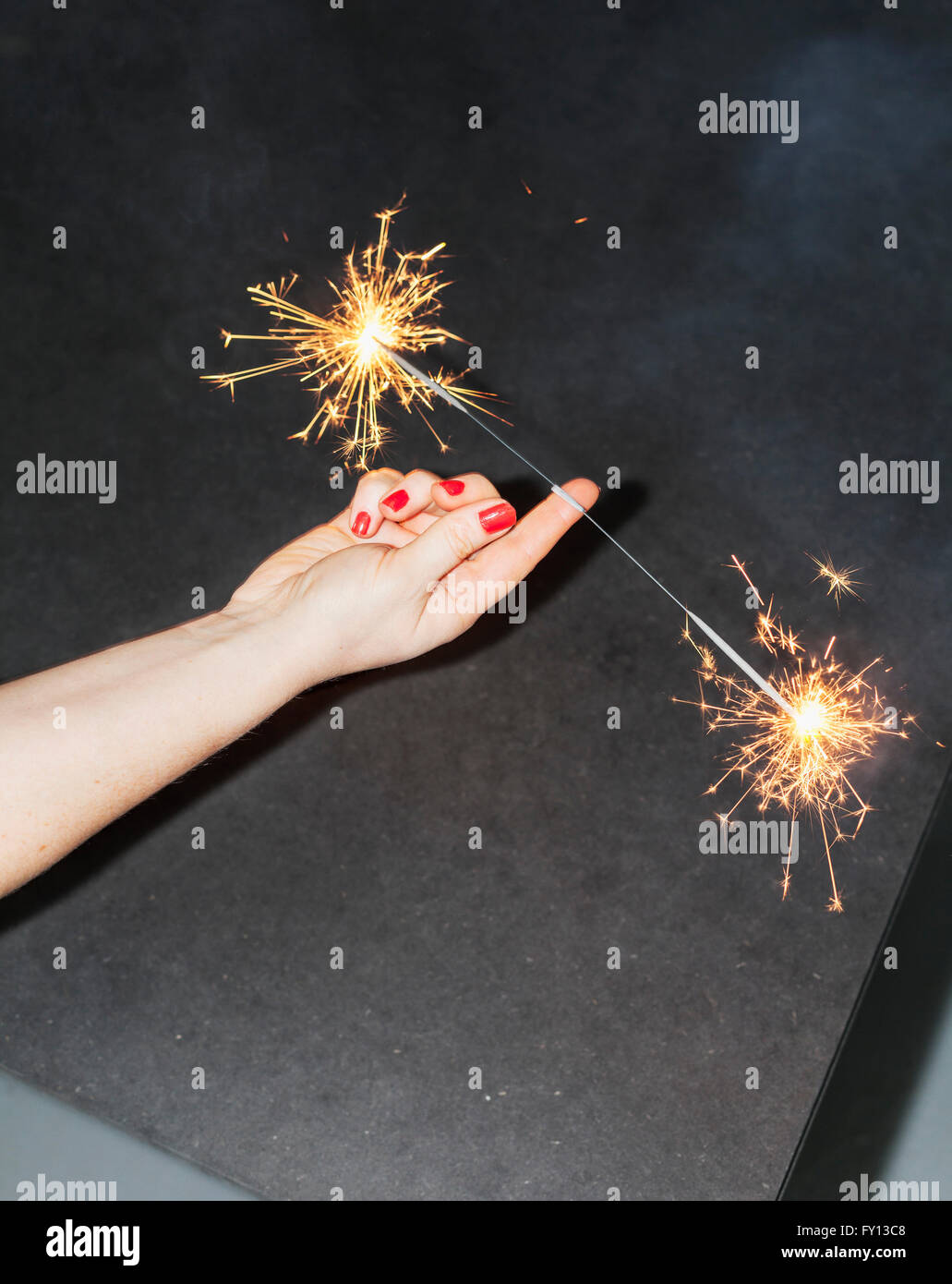 Cropped image of woman balancing sparklers on fingers Stock Photo