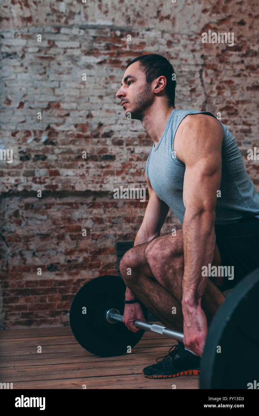 Determined young man lifting barbell at gym Stock Photo