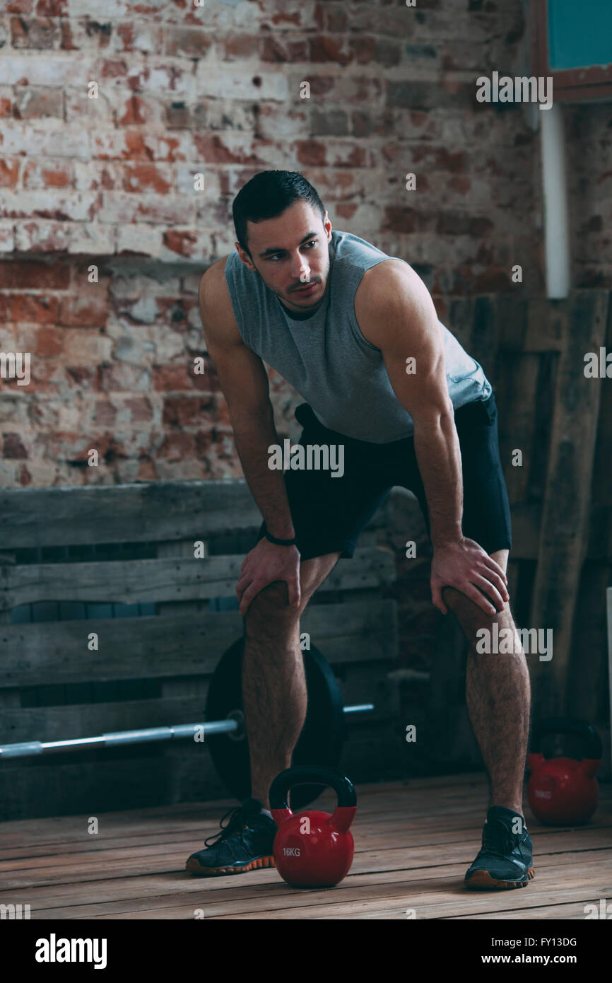 Tired athlete standing with hands on knees at gym Stock Photo