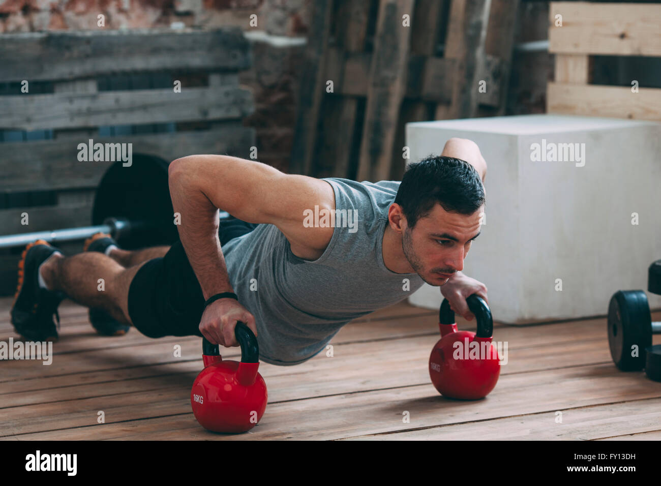 Dedicated man exercising with kettlebells at gym Stock Photo