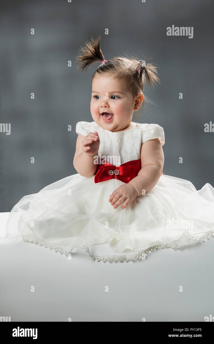 Cute baby girl with mouth open against gray background Stock Photo