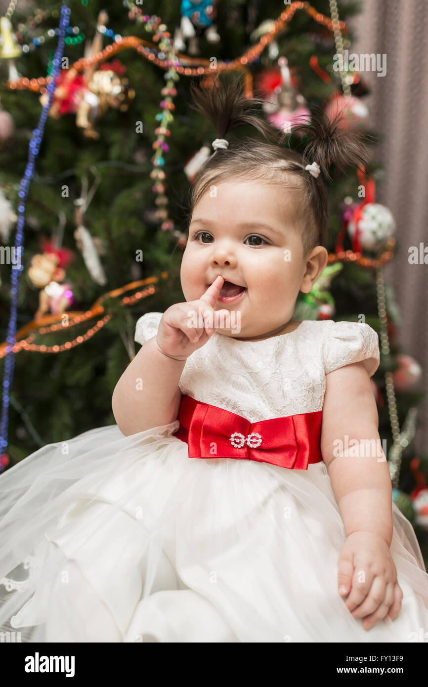 Cute baby girl sitting with Christmas tree in background Stock Photo