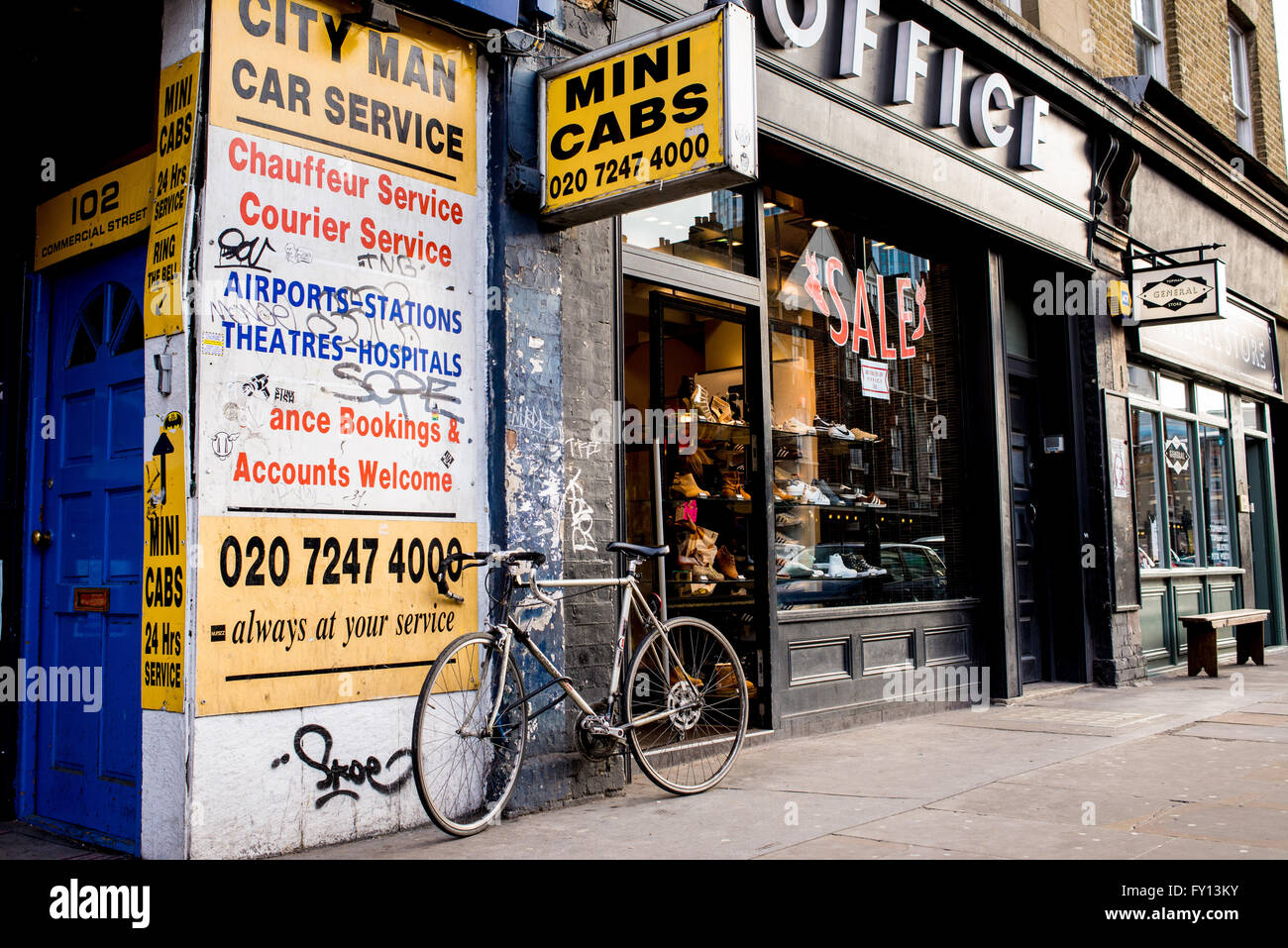 Mini cabs agency with old yellow billboards in a street in London. Bike parked in front. Stock Photo