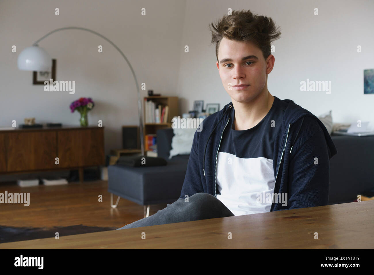 Portrait of teenage boy sitting by table at home Stock Photo - Alamy