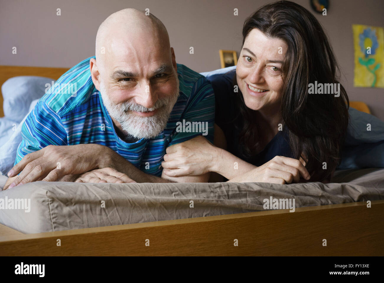 Portrait of happy mature couple lying on bed at home Stock Photo