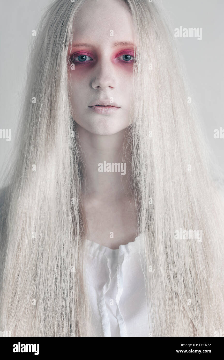 Young woman with spooky red eyes and long hair against white background Stock Photo