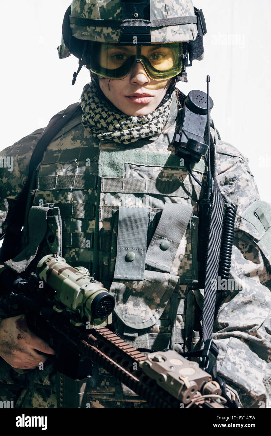Portrait of female soldier carrying rifle and standing against white background Stock Photo