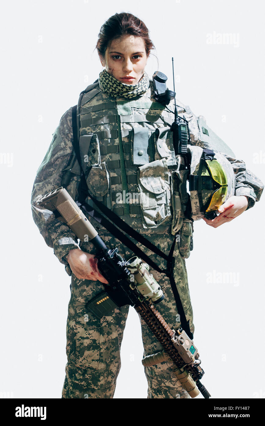 Portrait of soldier holding rifle and helmet standing against white background Stock Photo