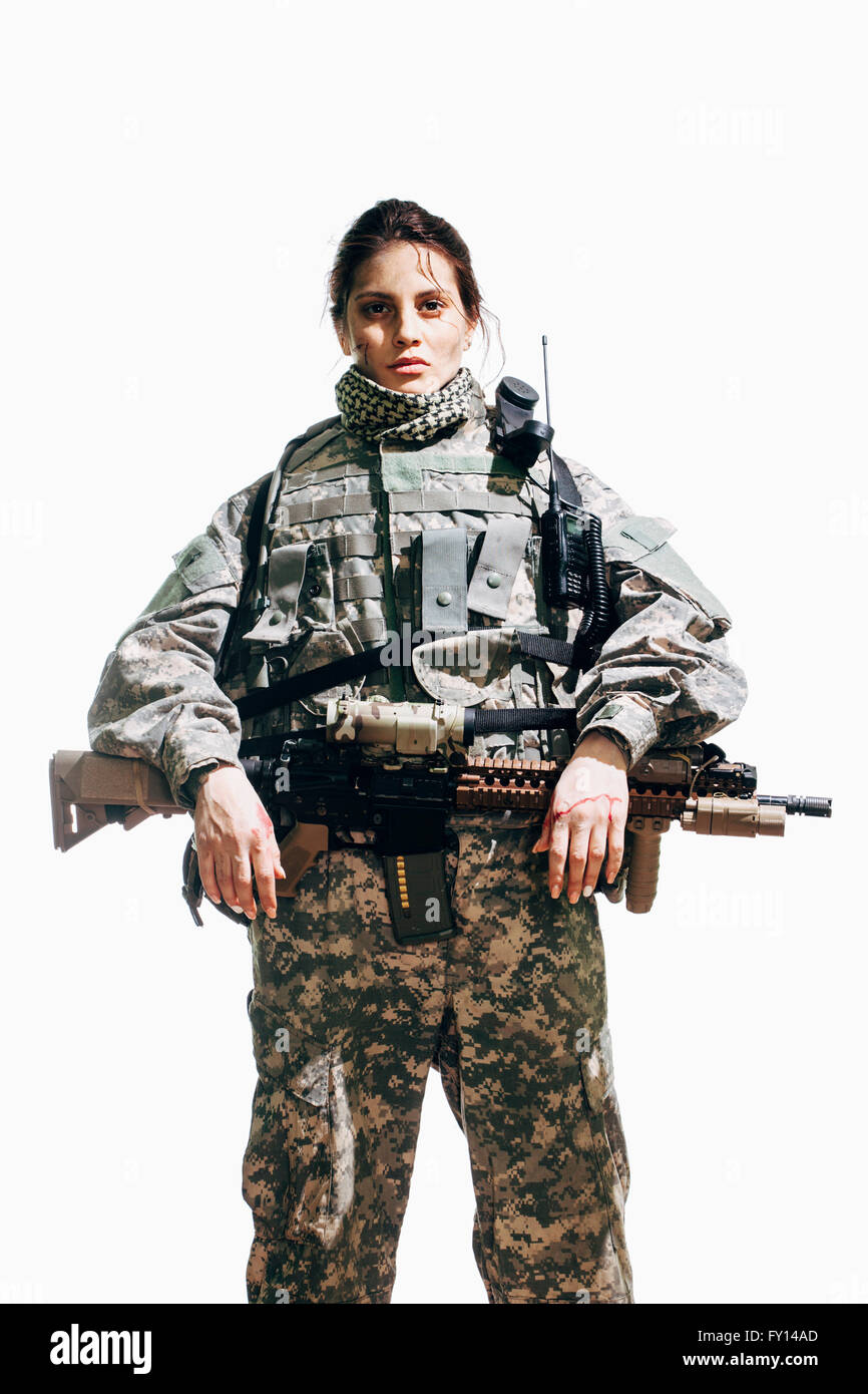 Portrait of female soldier standing with rifle against white background Stock Photo