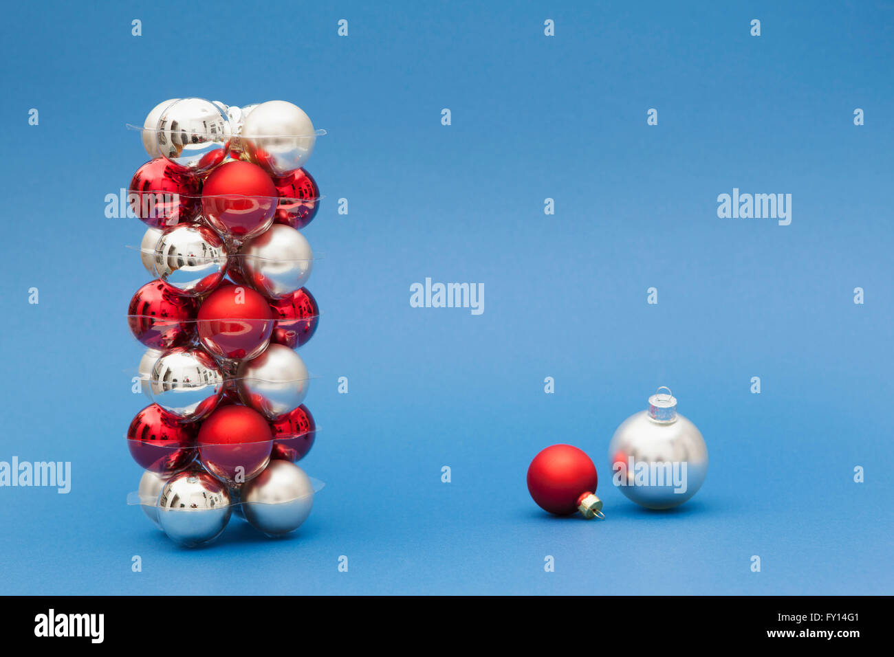 Stack of red and silver colored Christmas ornaments on blue background Stock Photo