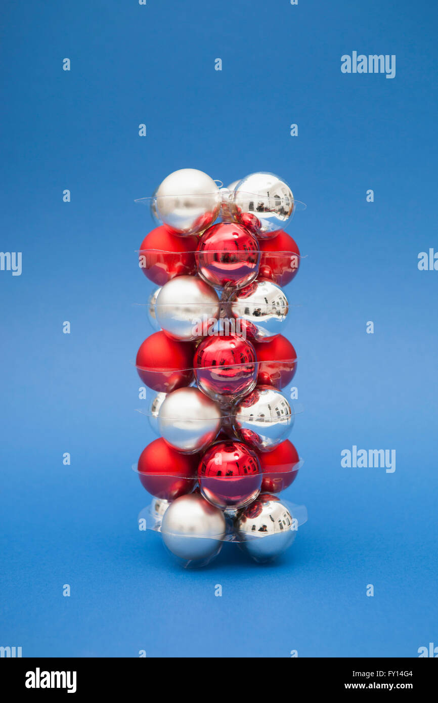 Stack of red and silver colored Christmas ornaments over blue background Stock Photo