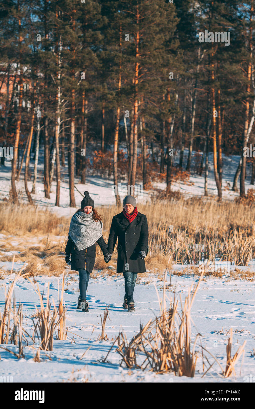 Young couple holding hands while walking on snow covered field Stock Photo