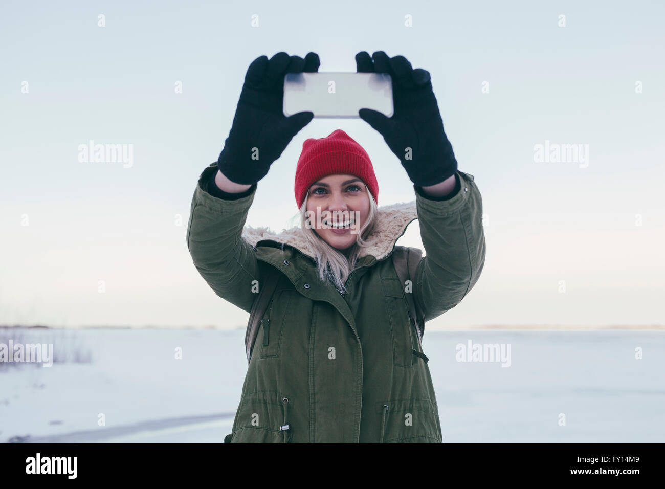 Young woman taking selfie on smart phone during winter Stock Photo