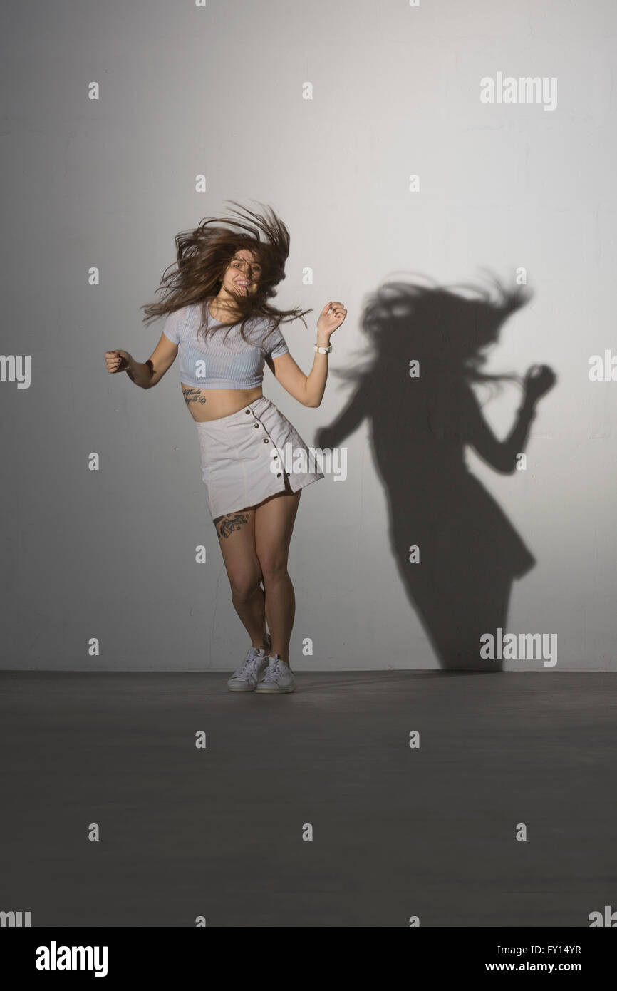 Full length of happy woman dancing against gray background Stock Photo