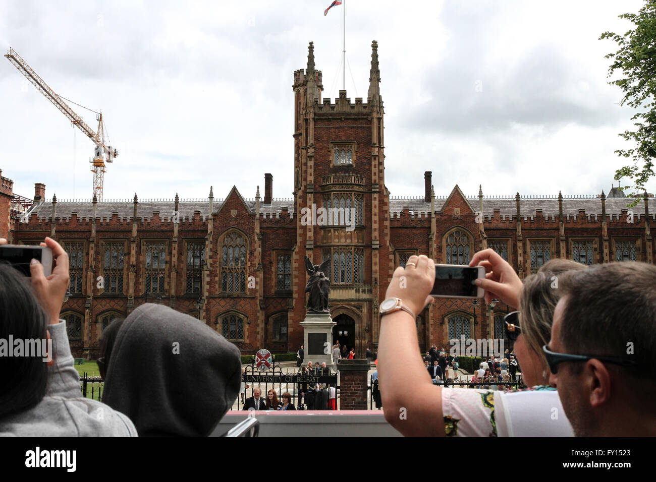 Tourists on Belfast tour bus taking photographs of The Queens University of Belfast and students on graduation day. Stock Photo