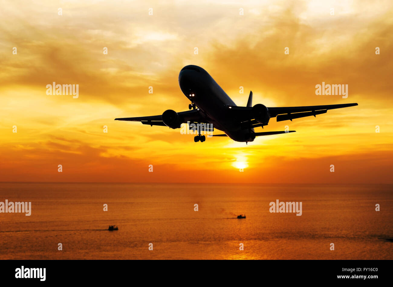 Airplane come down to the land on blurred sea sunset in twilight Stock Photo