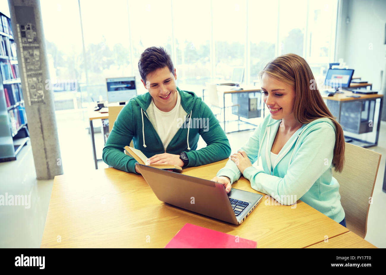 happy students with laptop and books at library Stock Photo - Alamy