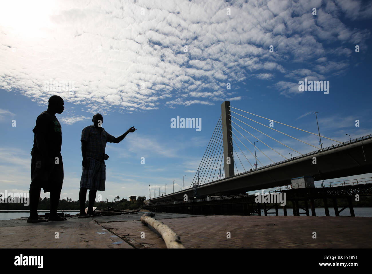 (160419) -- DAR ES SALAAM, April 19, 2016 (Xinhua) -- Two boatmen look at Kigamboni Bridge Dar es Salaam, Tanzania, on April 19, 2016. Tanzania's new 135-million-US-dollar bridge connecting Kigamboni and Kurasini in the east African nation's commercial capital Dar es Salaam, has left an indelible mark to local engineers. The project undertaken by China Railway Construction Engineering Group (CRCEG) in a joint venture with China Railway Major Bridge Group (CRMBG) was officially inaugurated by President John Magufuli on Tuesday. The 32-metre wide bridge has six lanes, three in each direction, an Stock Photo