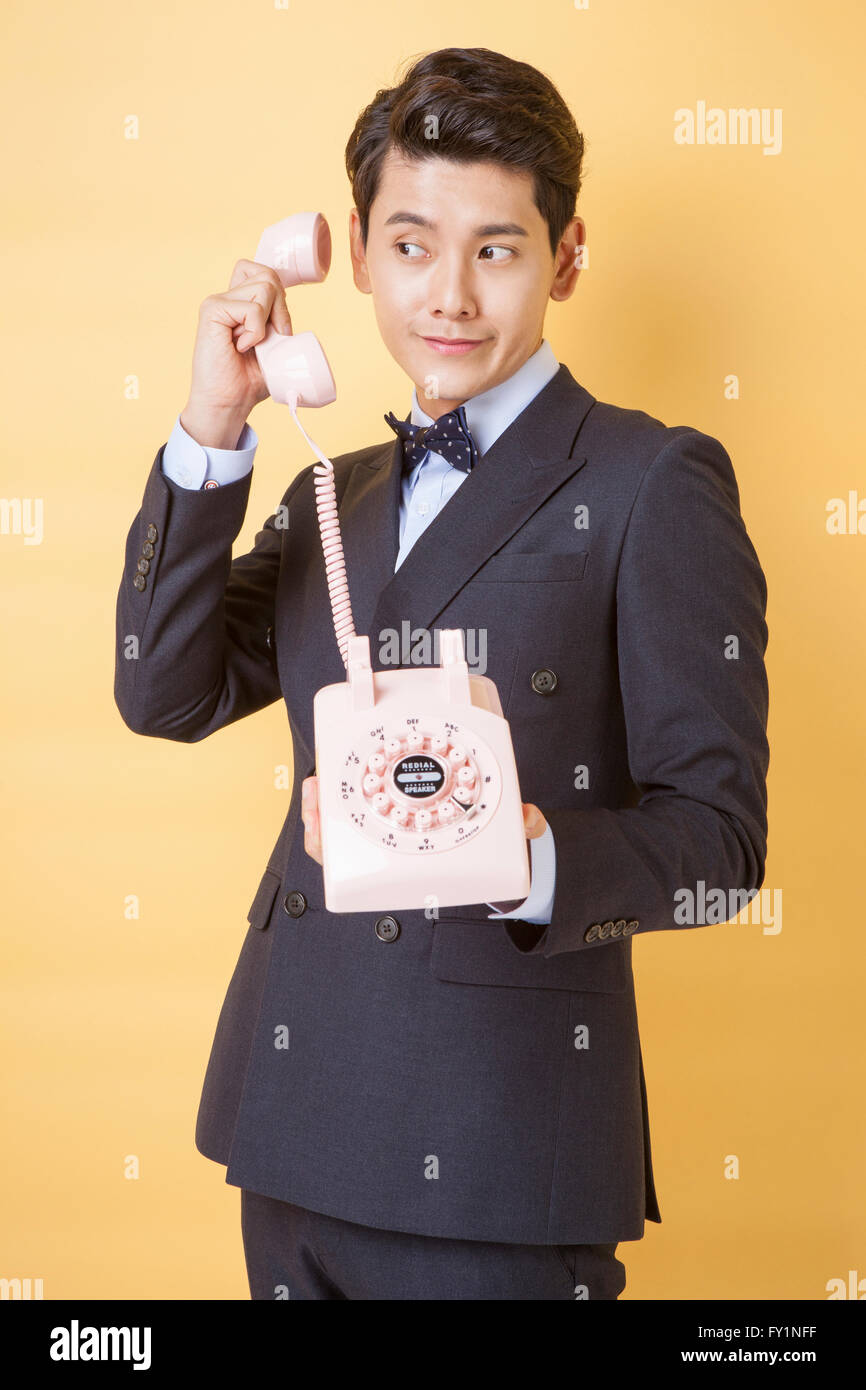 Young smiling business man in retro style suit holding a telephone ...