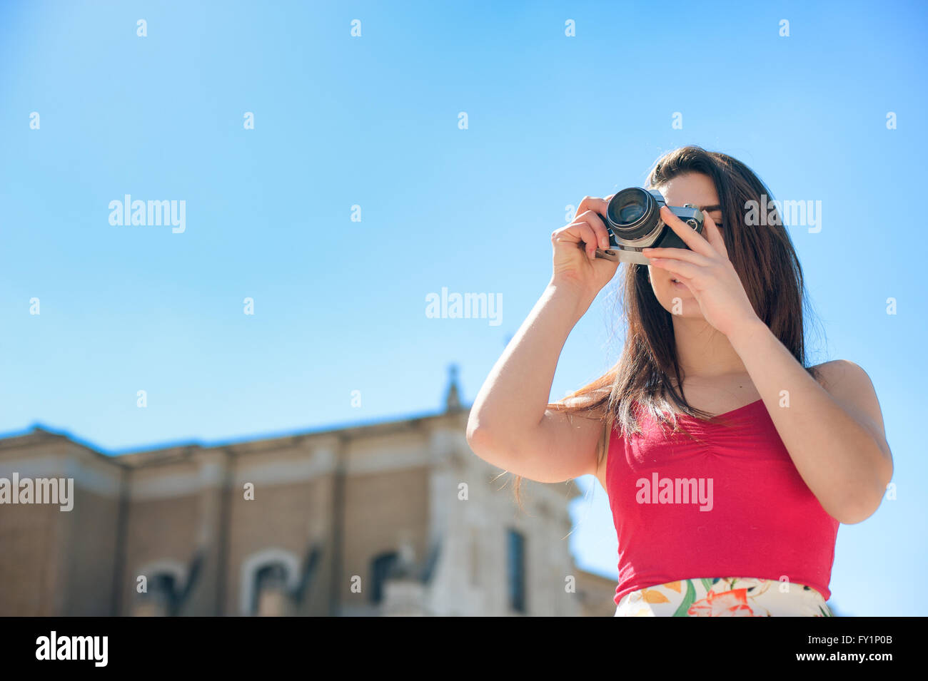 Young tourist woman taking picture with vintage camera outdoor in Rome Stock Photo