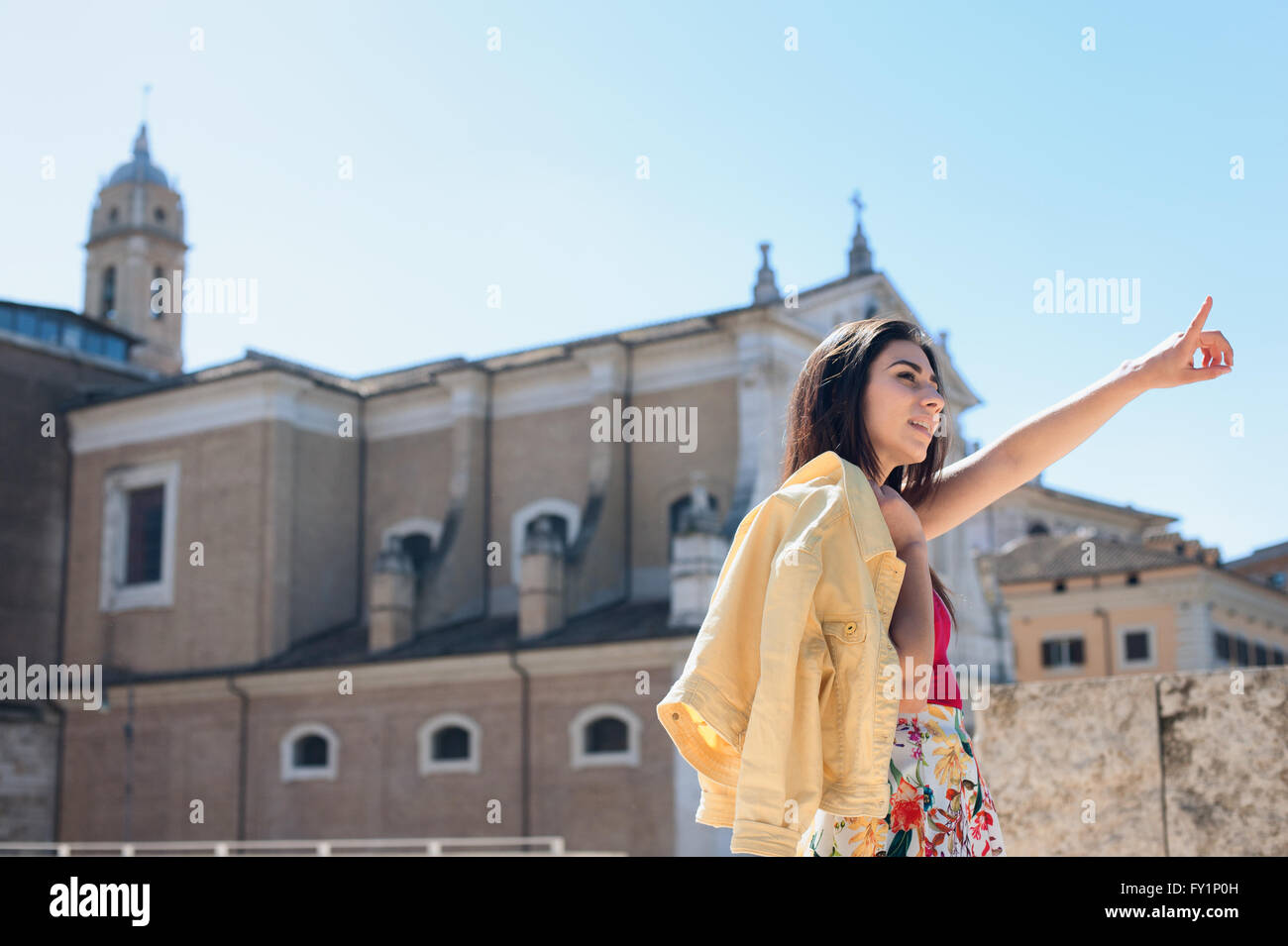 Young woman tourist summer pointing out outdoor with old churches in background Stock Photo