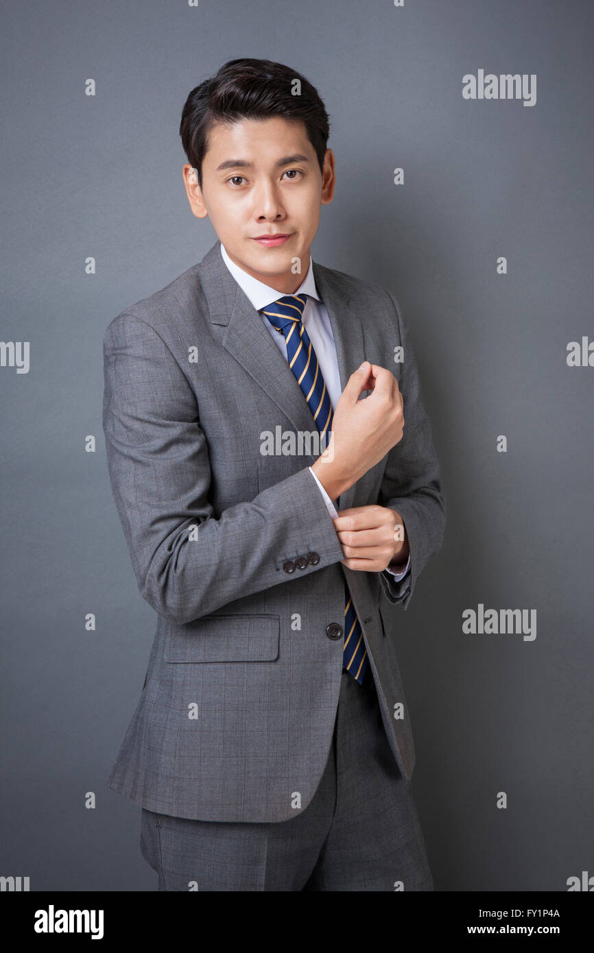 Young smiling business man in gray suit staring at front Stock Photo