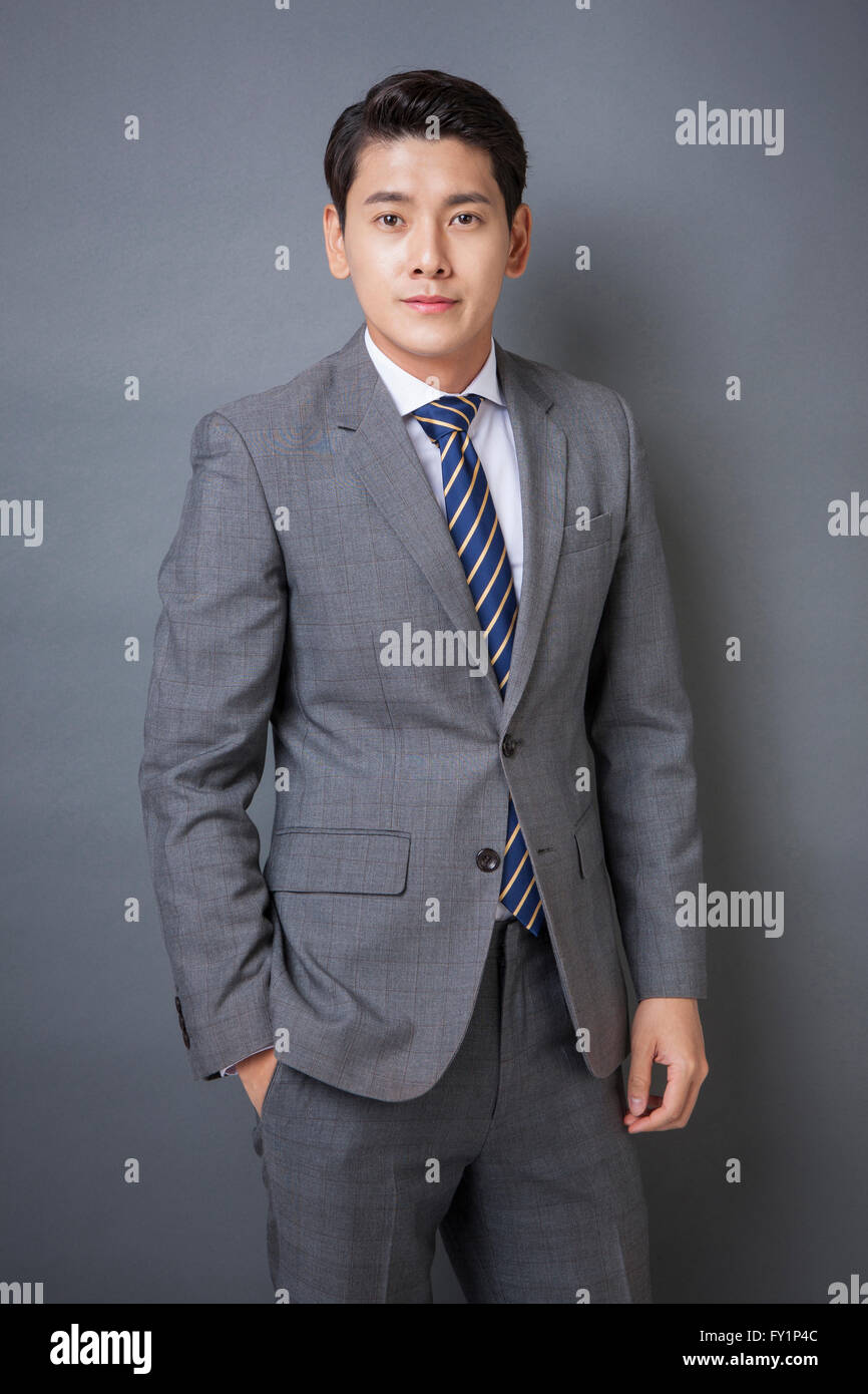 Young smiling business man in gray suit staring at front Stock Photo