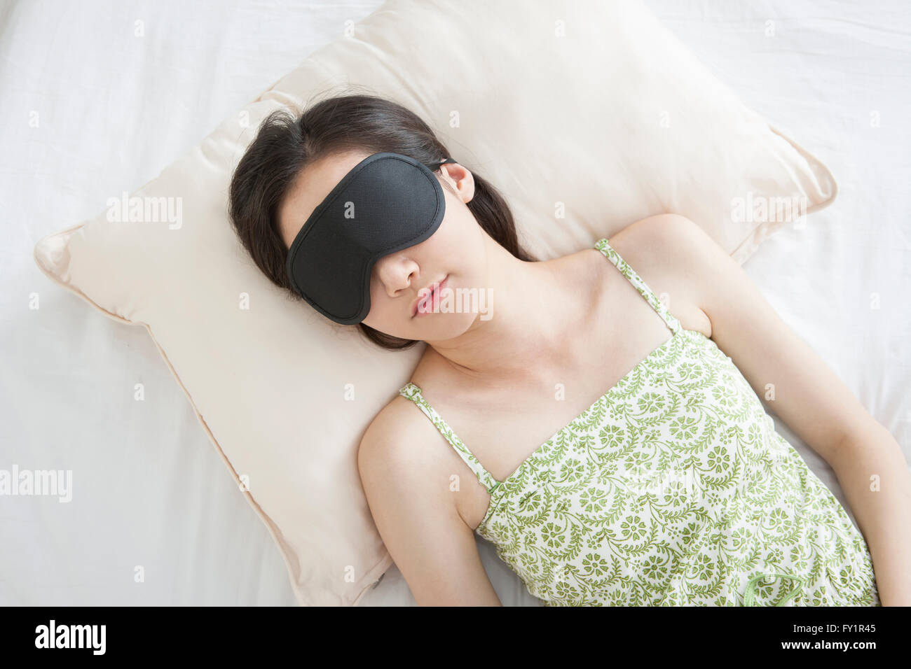 Hifh angle portrait of young woman lying down with a sleep shade Stock Photo