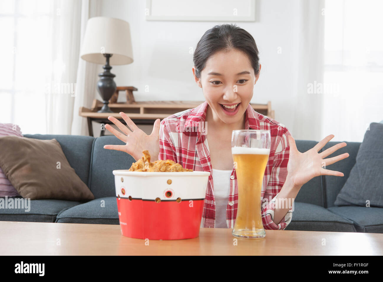 Portrait of young smiling woman delighted with fried chicken and beer Stock Photo