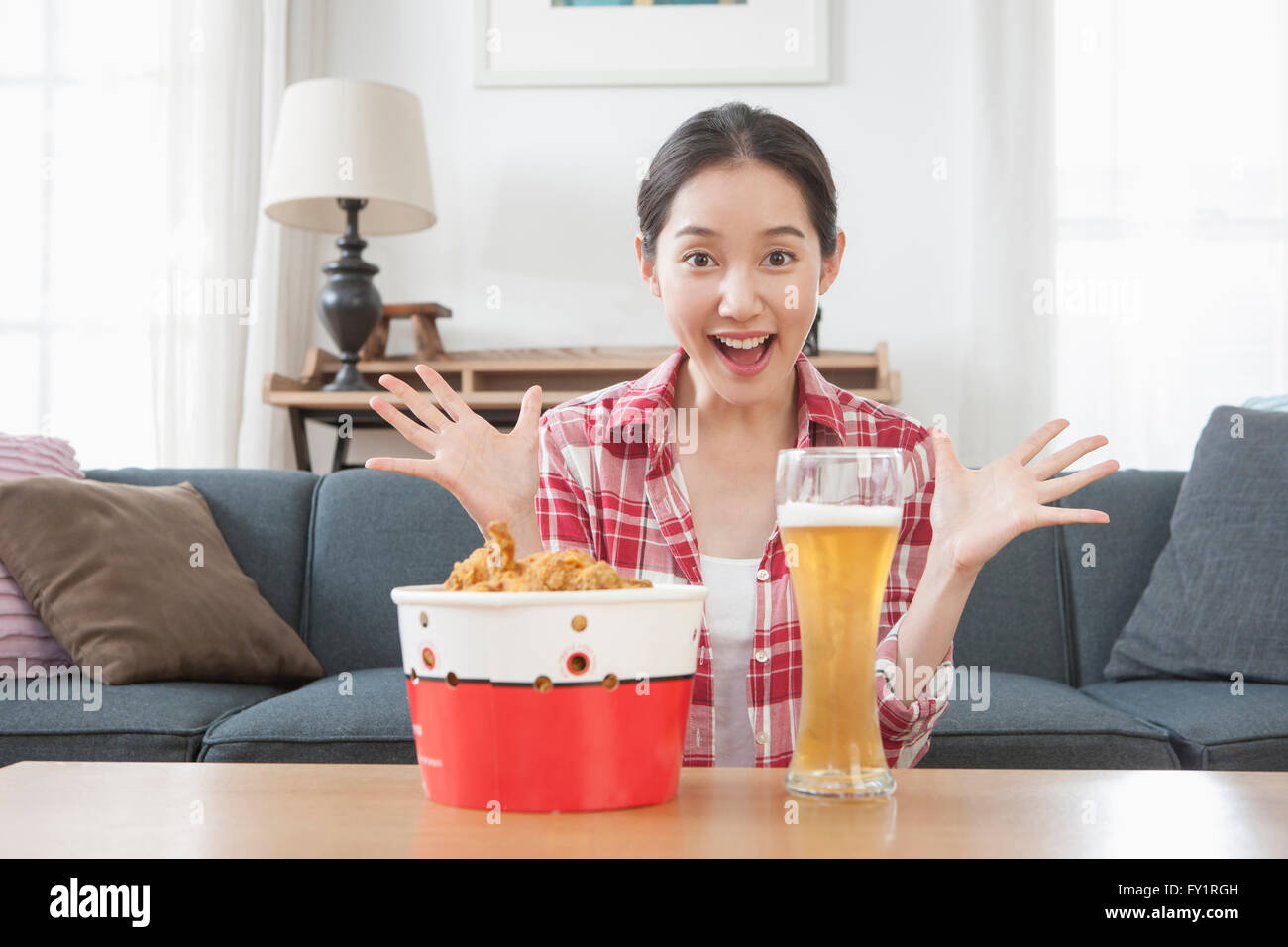 Portrait of young smiling woman delighted with chicken and beer Stock Photo