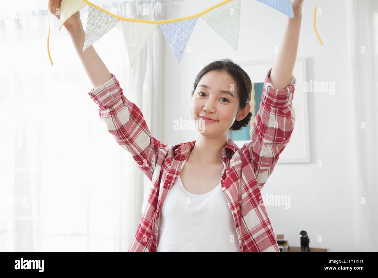 Portrait of young smiling woman holding party flags staring at front ...