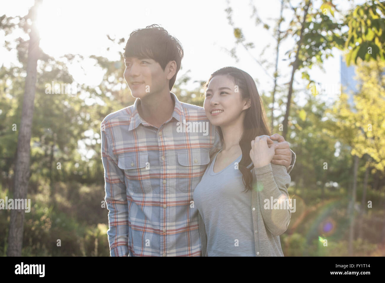 Portrait of young smiling couple hugging at park Stock Photo - Alamy