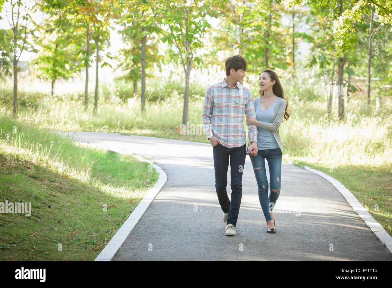 Young smiling couple walking hand in hand at park Stock Photo - Alamy