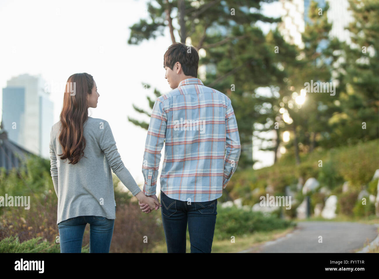 Back of young couple walking hand in hand at park Stock Photo - Alamy