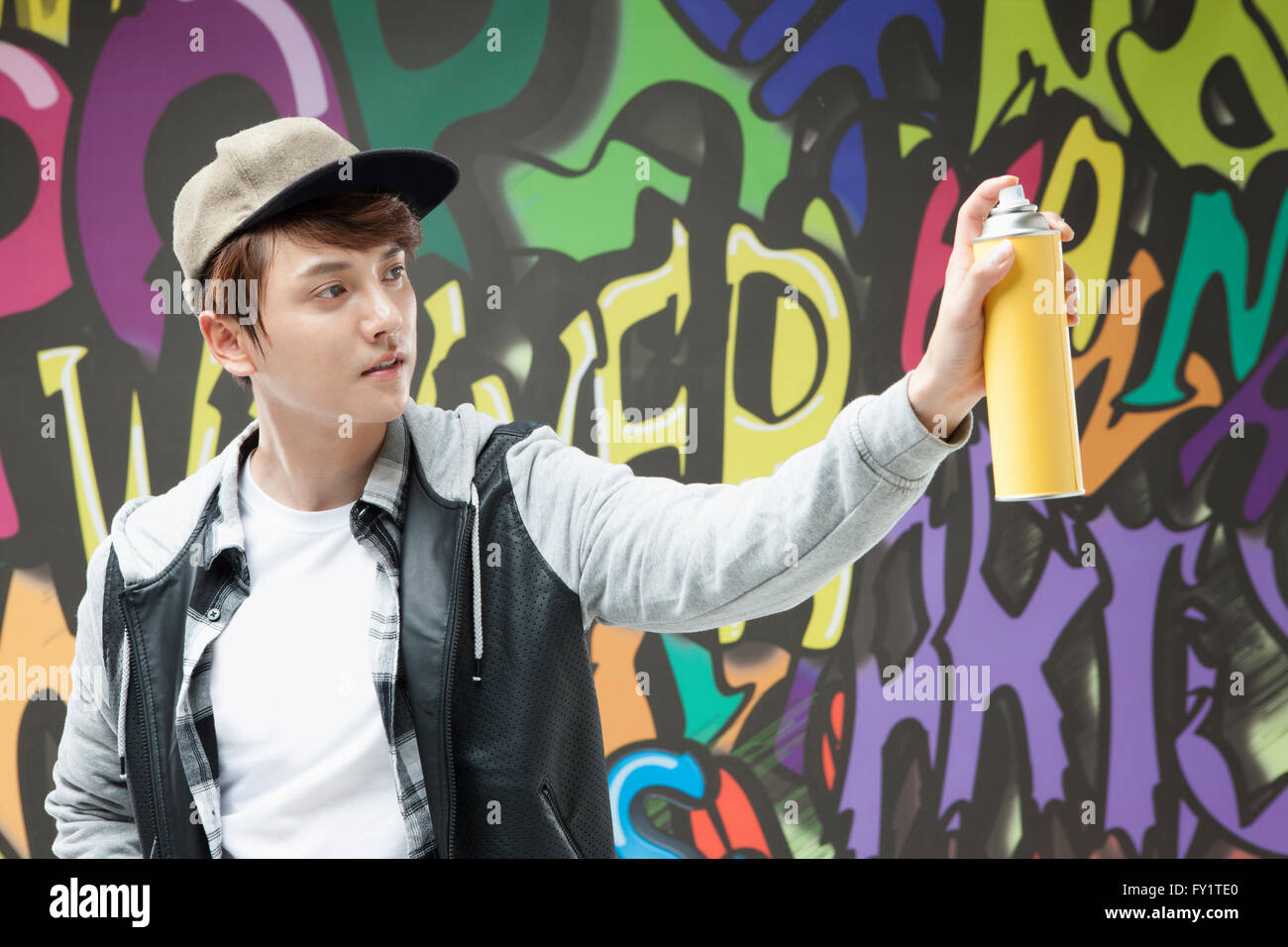 Portrait of young man in hip-hop style holding a spray against graffiti art Stock Photo