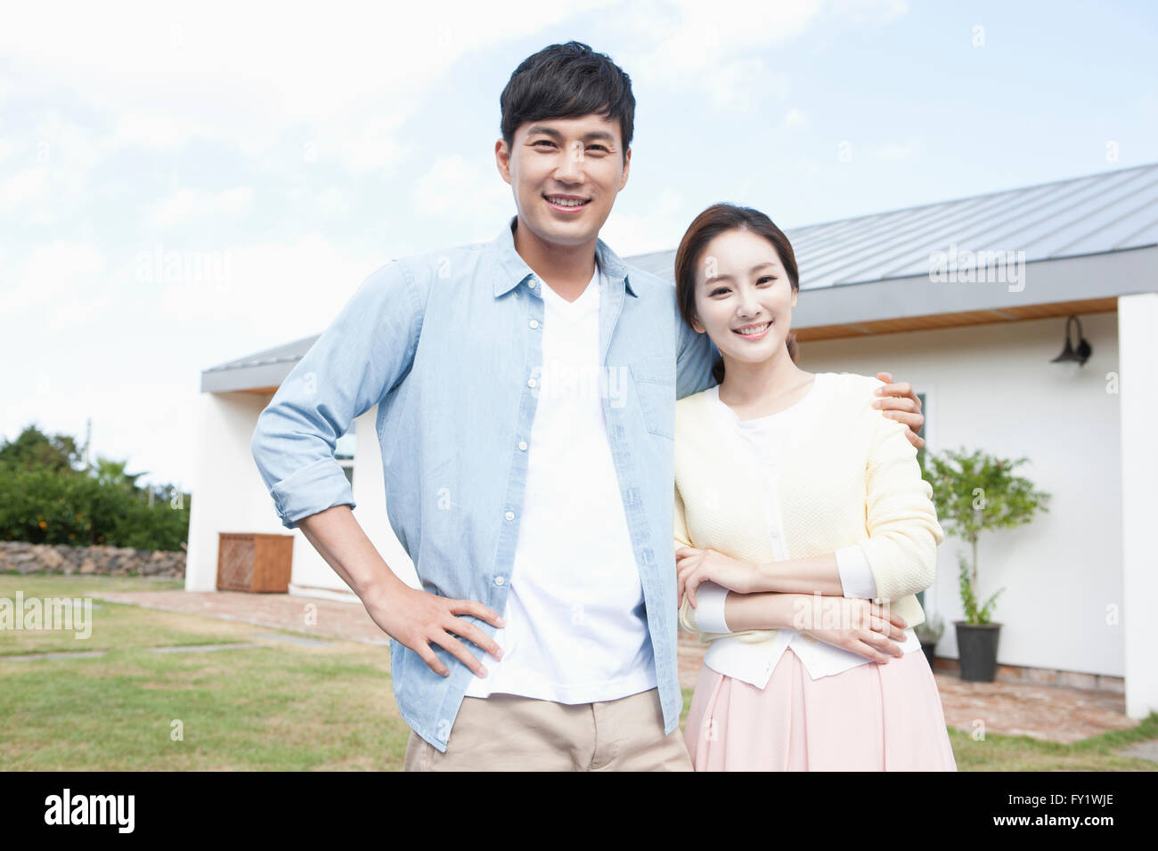 Couple staring forward with a smile at the yard of their house in Jeju Stock Photo