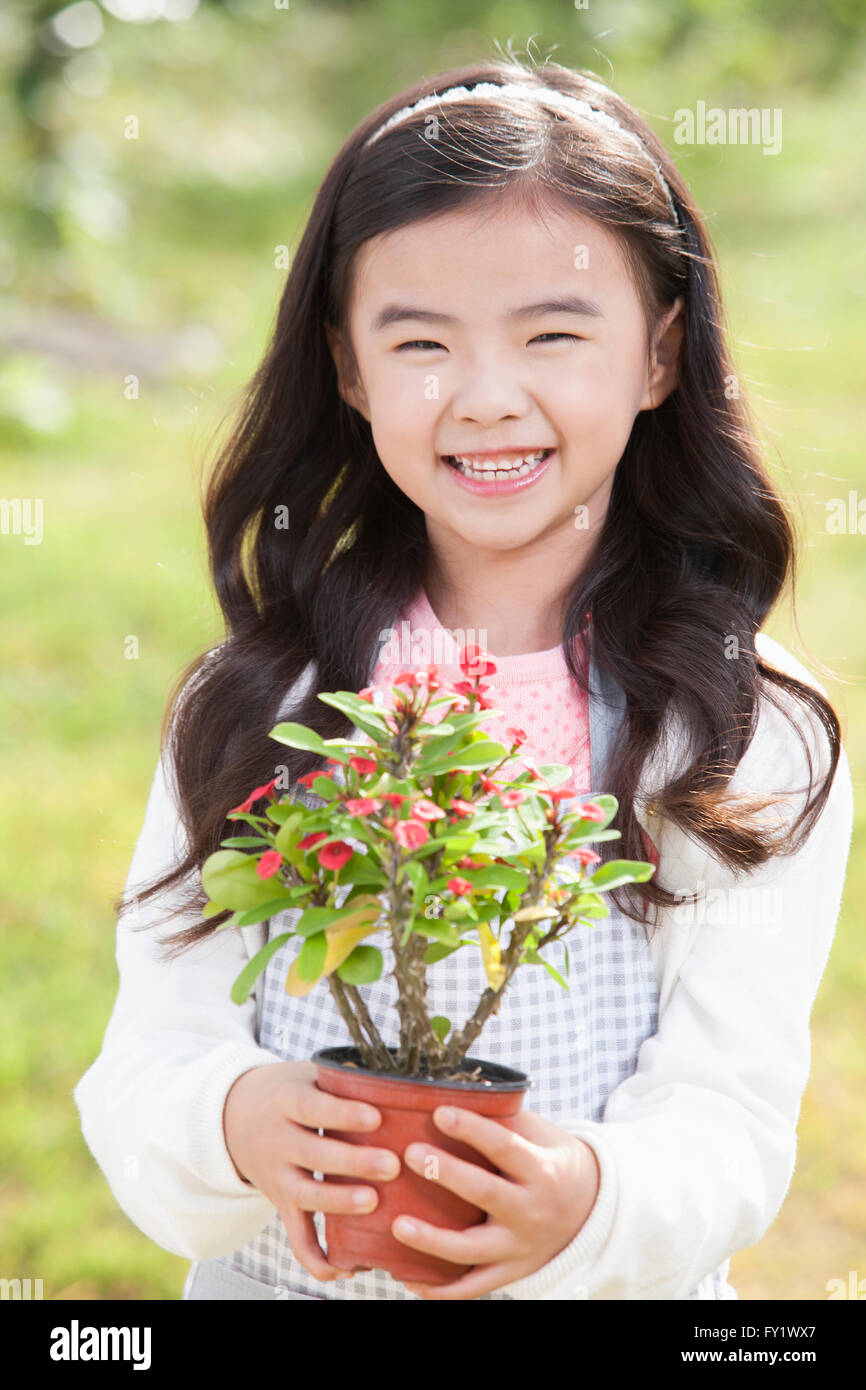 Girl holding a plant pot and smiling Stock Photo