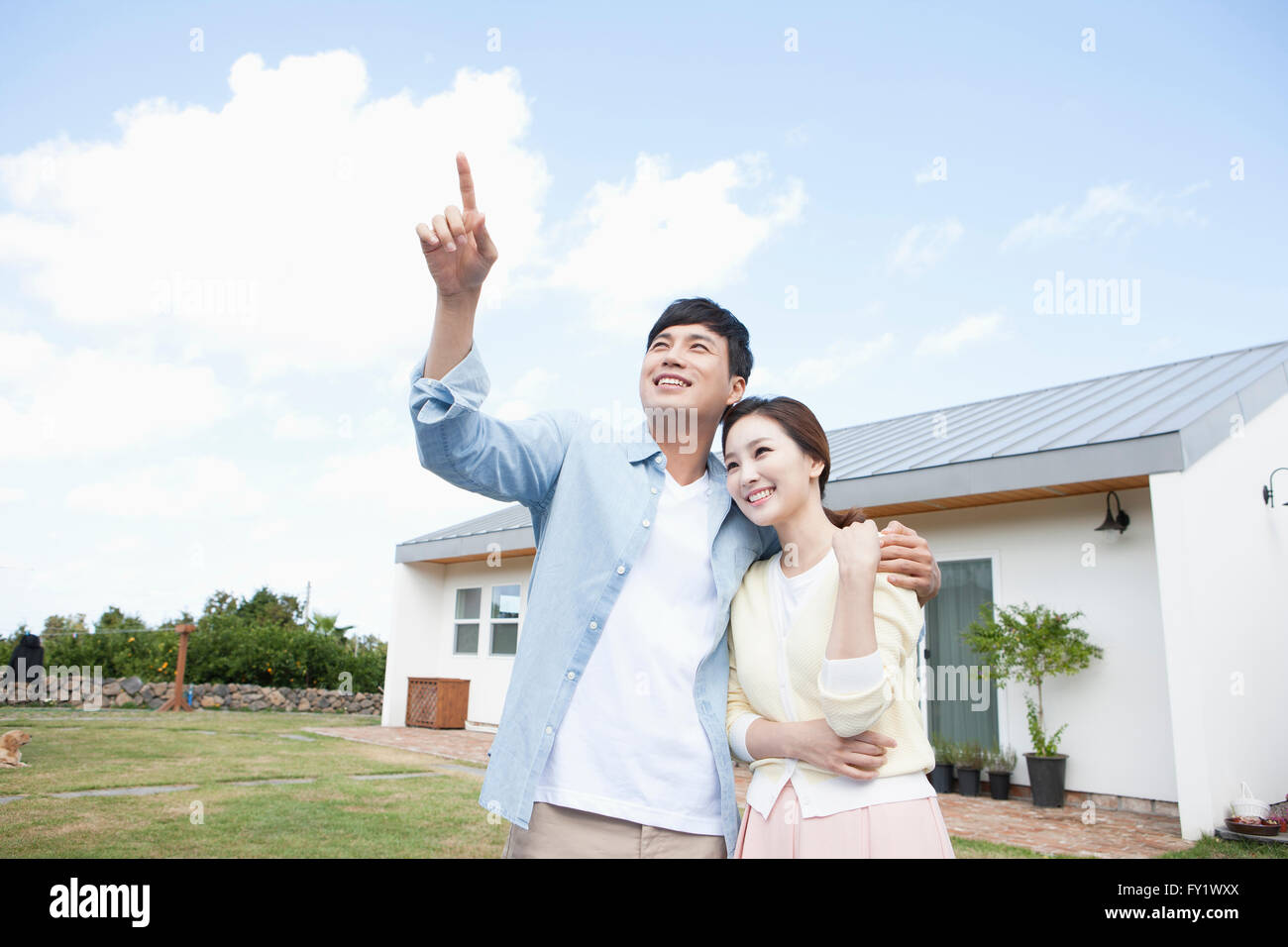 Couple looking up with a smile at the yard of a house representing rural life Stock Photo