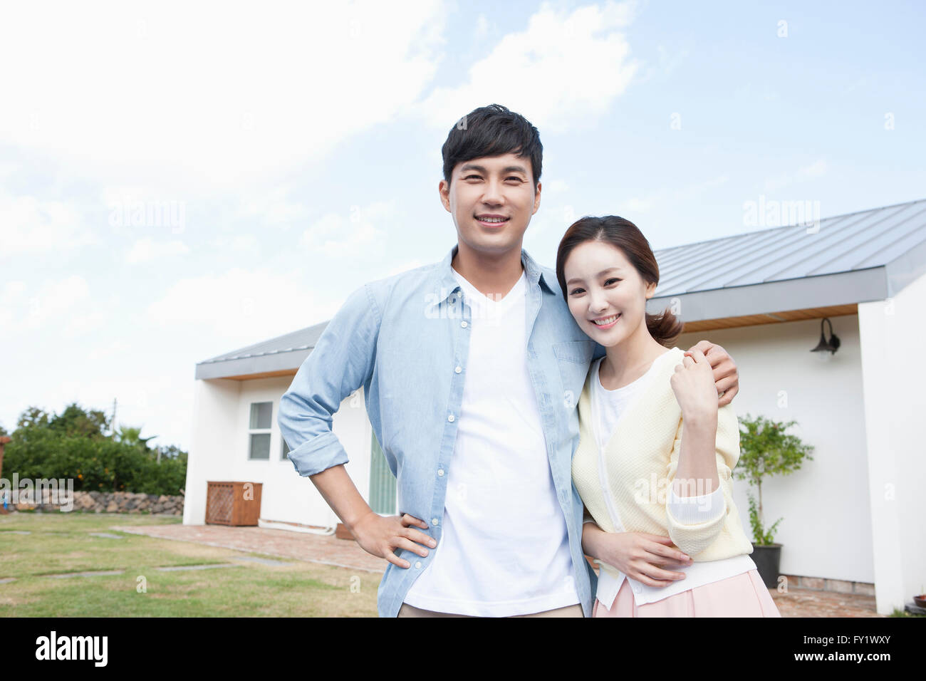 Couple staring forward with a smile at the yard of a house representing rural life Stock Photo
