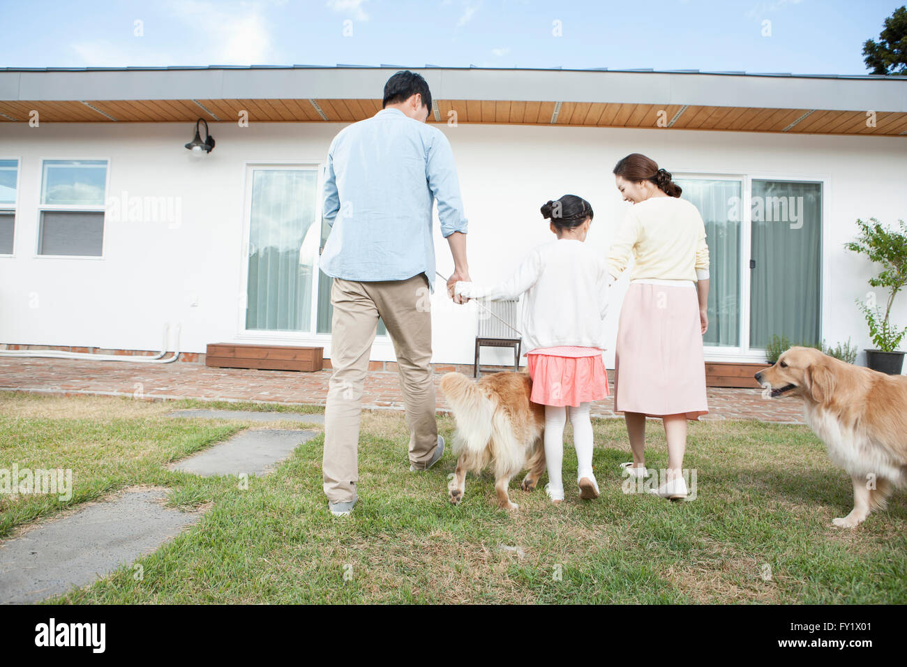Back appearance of a family with dogs at the yard of their house representing rural living Stock Photo
