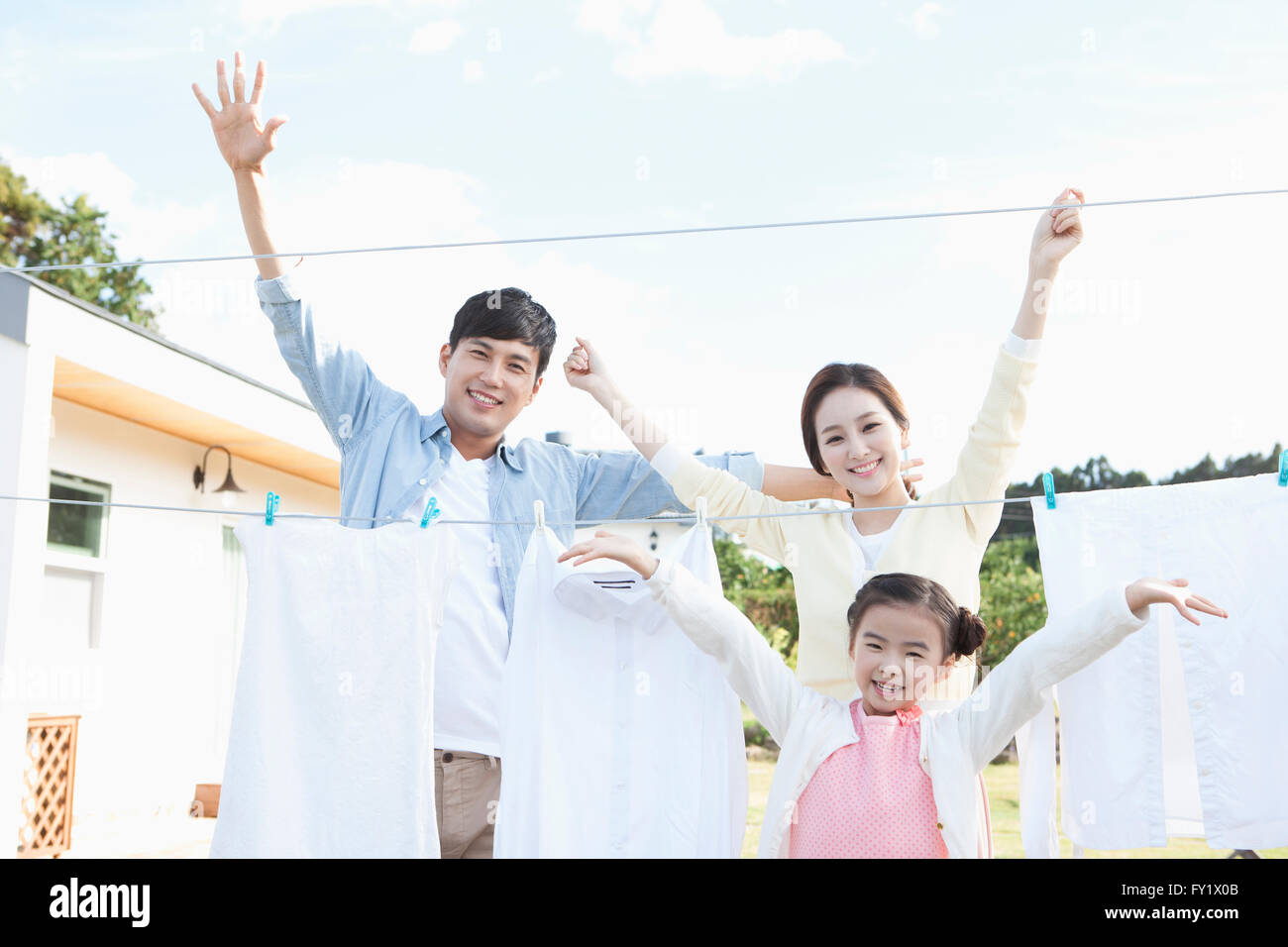Family being happy doing laundry together at the yard of their house representing rural living Stock Photo