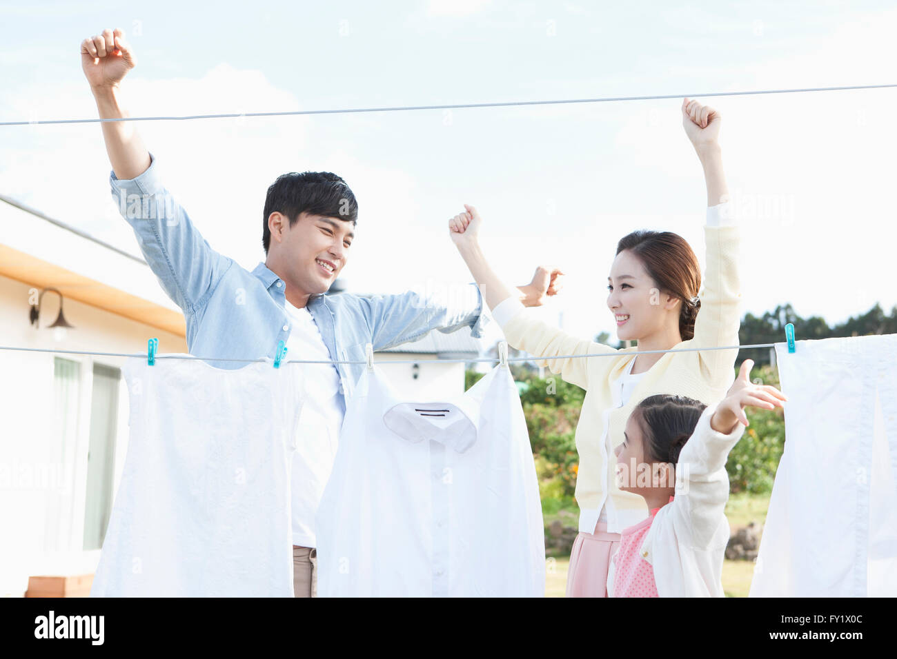 Family being happy doing laundry together at the yard of their house representing rural living Stock Photo