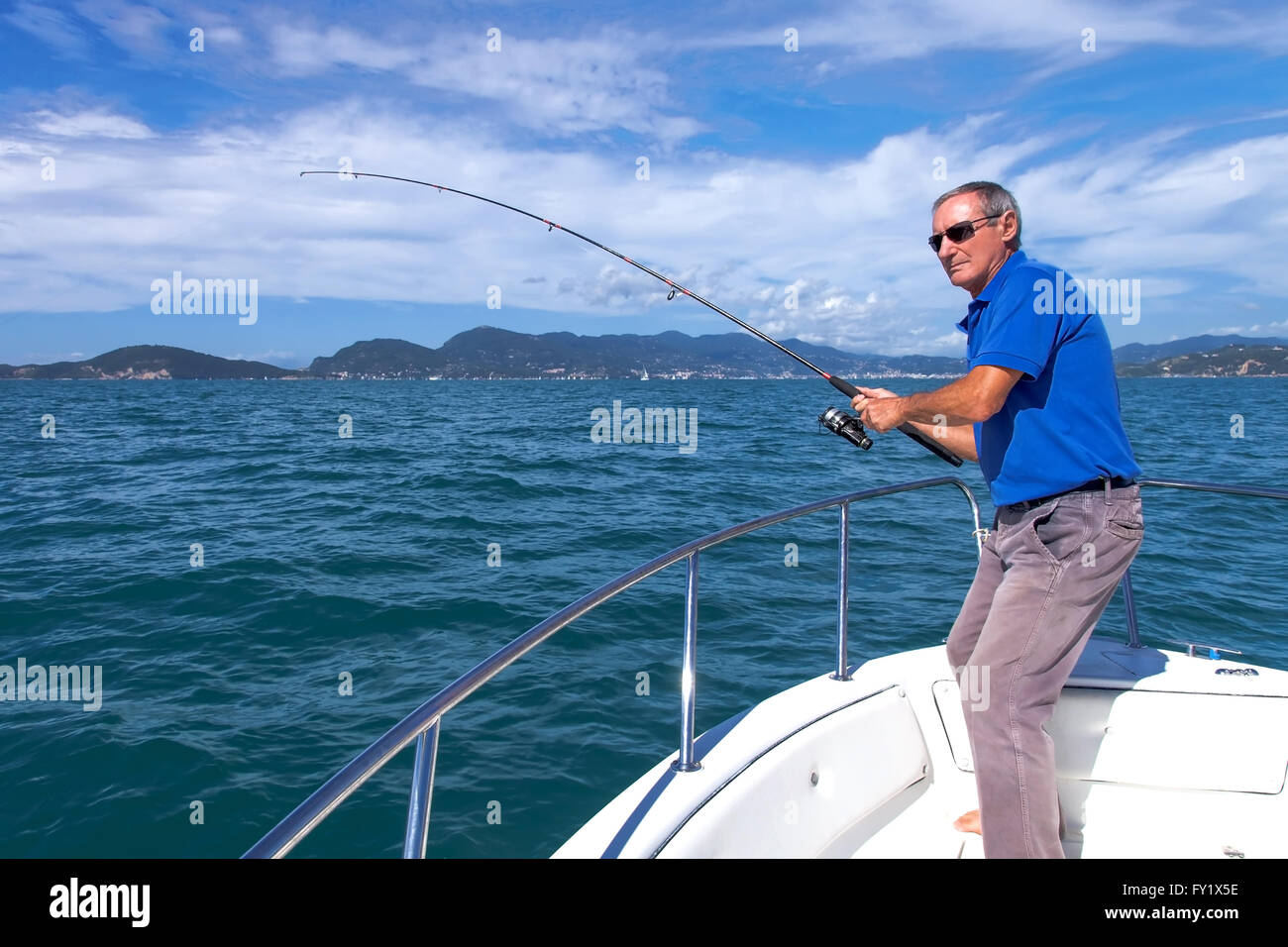 Angler fisherman fighting big fish on the ocean from the boat Stock Photo