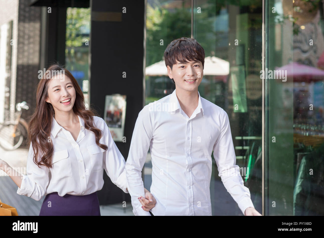 Couple with their arms locked to each other and smiling forward Stock