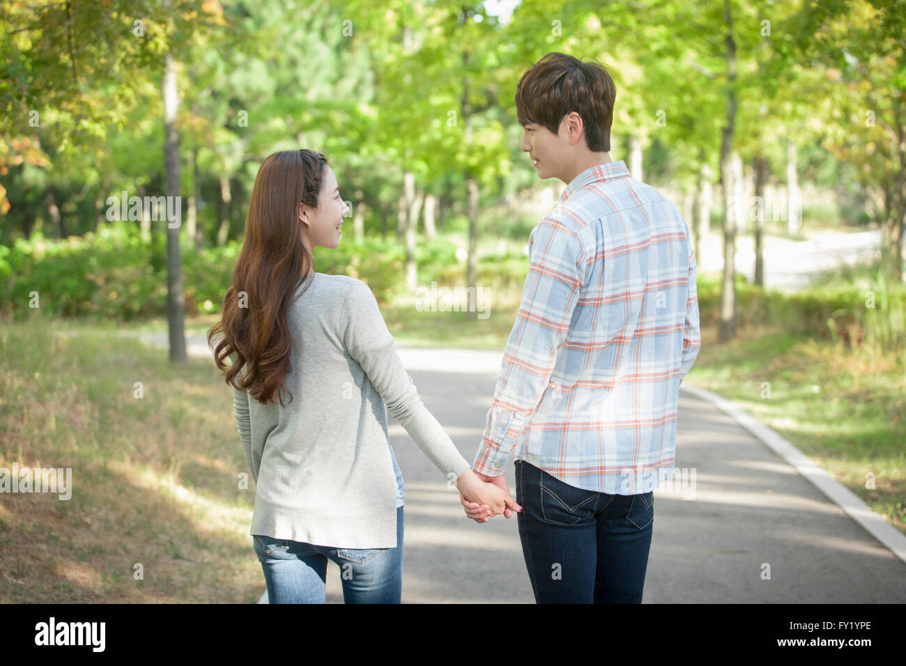 Back appearance of a couple walking hand in hand at the park Stock ...