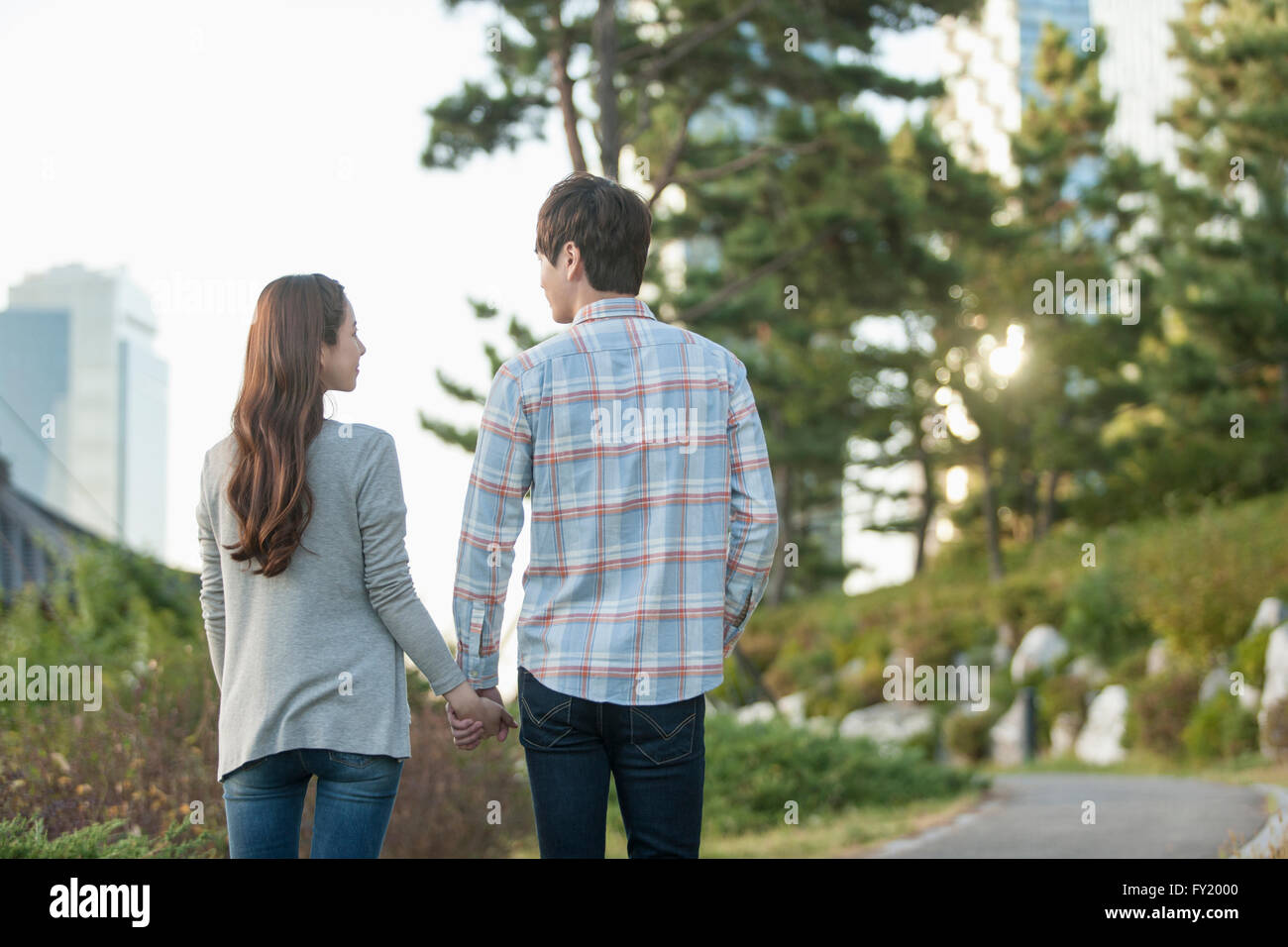 Back appearance of a couple walking hand in hand at park Stock Photo ...