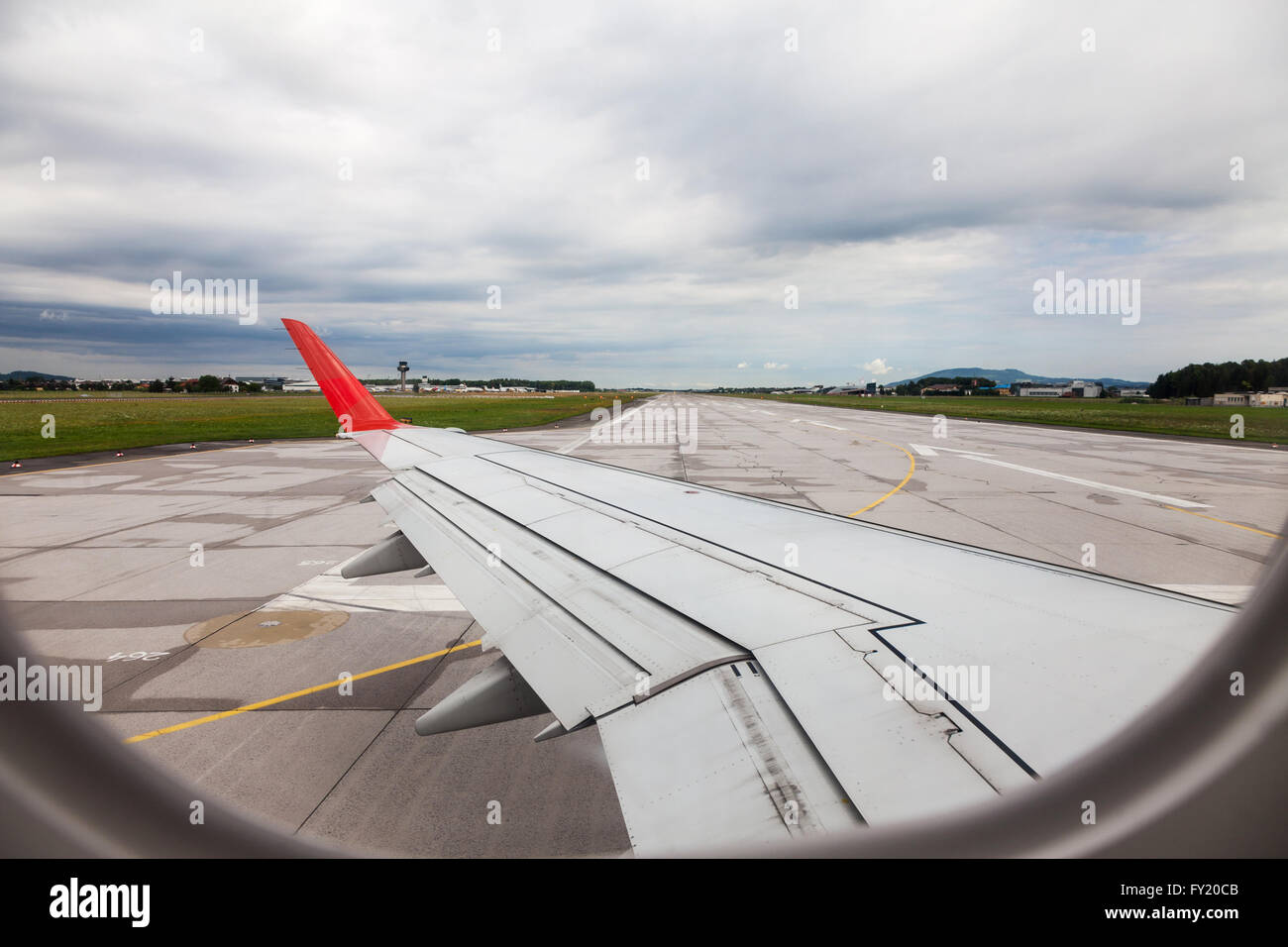 Looking through an airplane window at the runway taxiing on takeoff at Salzburg airport Salzburg Austria Europe Stock Photo