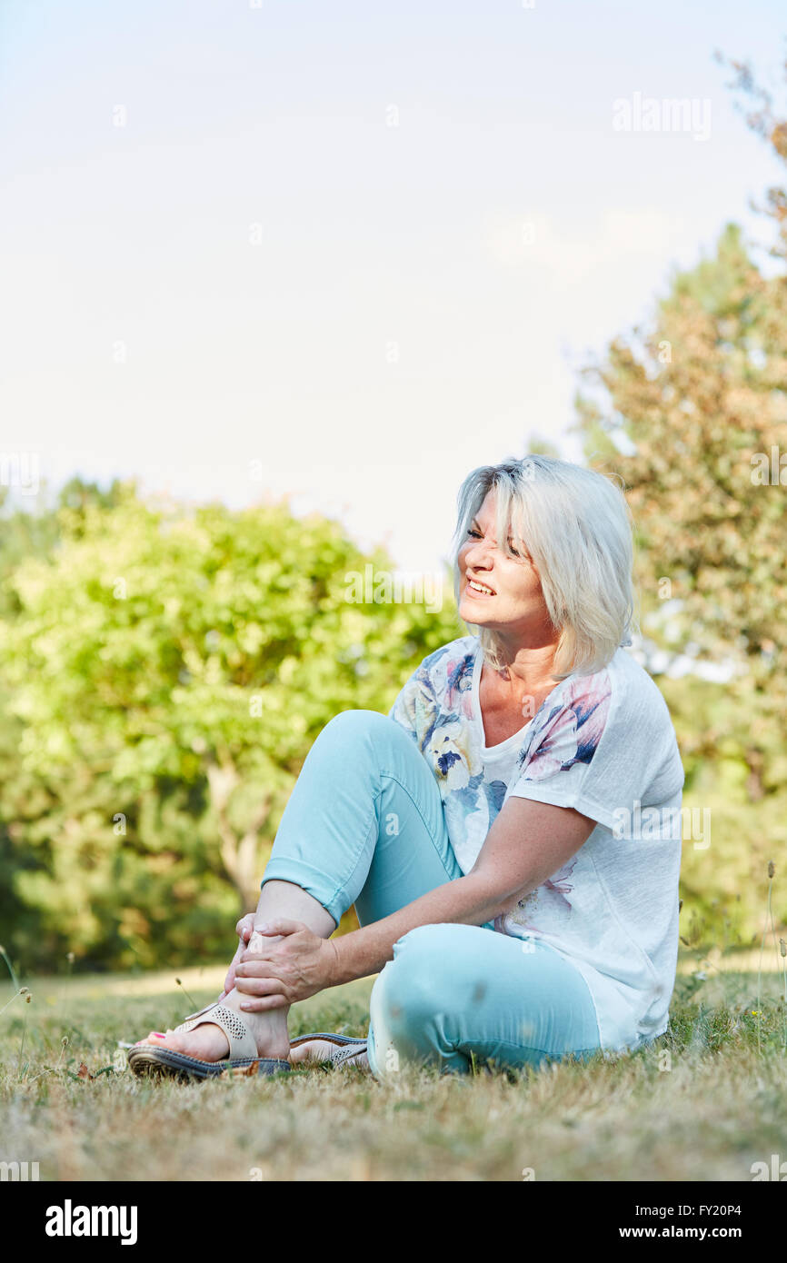Senior woman with sprained foot with pain in the park Stock Photo