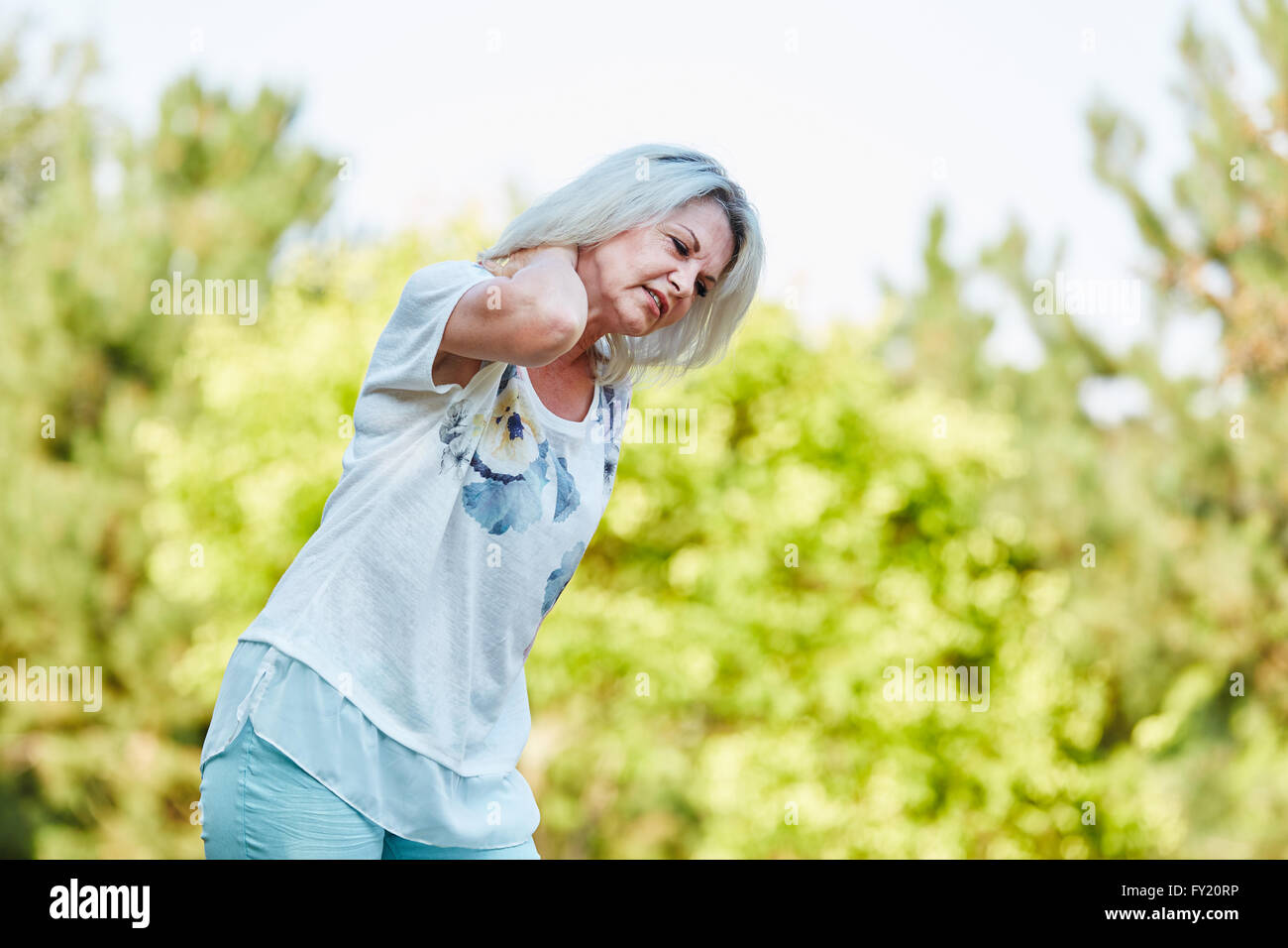 Senior woman with neckpain while walking in the nature Stock Photo