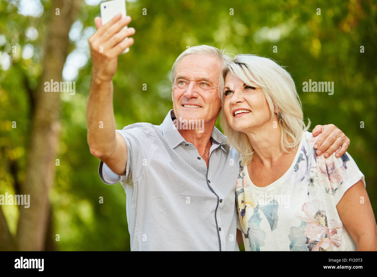 Senior couple taking a selfie with smartphone in summer in the nature ...